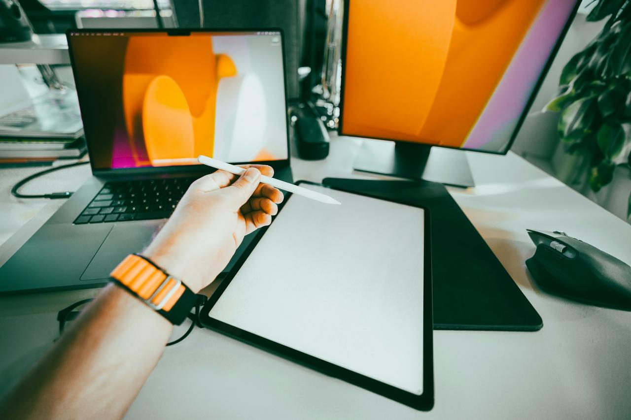 A person's hand on a clipboard next to a computer monitor